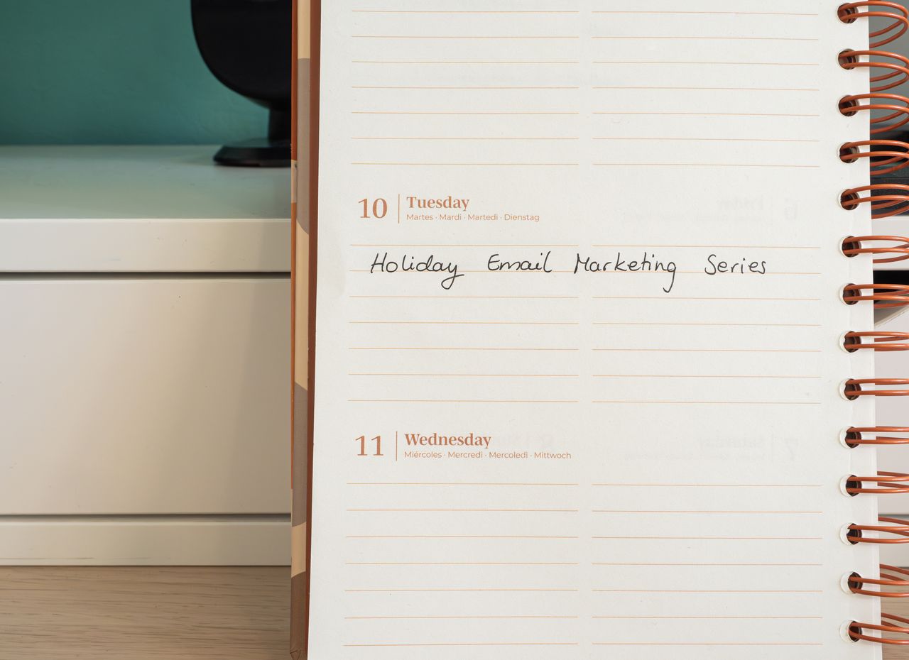 services-04 Un agenda ouvert sur un bureau avec une note manuscrite « Holiday Email Marketing Series ».